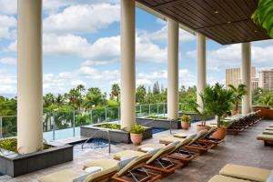 a hotel patio with chairs and a pool and palm trees at Ka Laʻi Waikiki Beach, LXR Hotels & Resorts in Honolulu