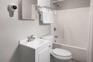 a white bathroom with a toilet and a sink at Days Inn by Wyndham Moosic in Moosic +22 photos