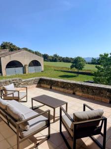 a patio with a table and chairs and a stone wall at Mas Català in Rupiá