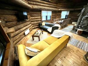 a living room with a couch in a log cabin at Villa Pukelo Arctic Lodge with wifi sauna 4 poster bed fireplace in Salla
