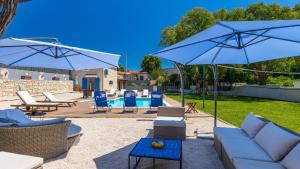 a patio with blue chairs and umbrellas at Lukini dvori by Villas Guide in Bibići