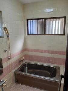 a bath tub in a bathroom with a window at 民宿なかやま in Kushimoto