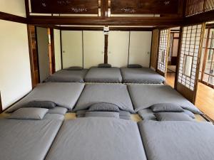 a group of beds in a room with windows at 見晴らしの宿 Guest House景 in Kumamoto