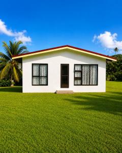 a white house with a green lawn at Mouare Hideaway in Arutanga