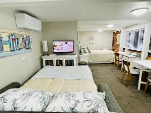 a bedroom with two beds and a tv in it at Whitby Studio - Mairangi Bay Beach in Auckland