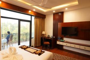 a hotel room with a bed and a tv and a balcony at Paragon Hotel & Resort in Sreemangal