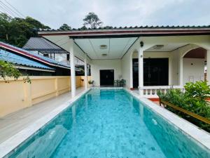 a swimming pool in front of a house at Coconut hill villa in Trat