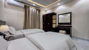 a hotel room with two beds and a television at قصر لوماج - احد رفيدة in Ahad Rafidah
