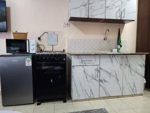 a kitchen with a black stove and a refrigerator at PiemStays in Ruaka