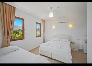 a white bedroom with two beds and a window at Arzu otel apart in Datca