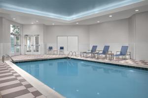 a large swimming pool with blue chairs in a room at Embassy Suites by Hilton Birmingham Hoover in Birmingham