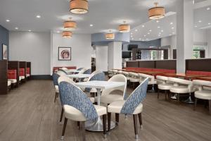 a restaurant with white tables and chairs and red seats at Embassy Suites by Hilton Birmingham Hoover in Birmingham