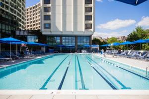 a large swimming pool with chairs and blue umbrellas at Washington Hilton in Washington, D.C.