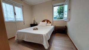 a bedroom with a white bed and two windows at La Casina de L'Aspu in Luces