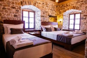 two beds in a room with stone walls and windows at Vila Blin in Berat
