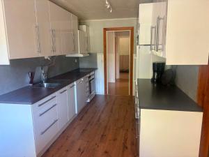 a kitchen with white cabinets and a wooden floor at Villa Konga in Konga