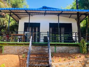 a house with a porch and stairs in front of it at Tunnel Gap Homestay in Ella