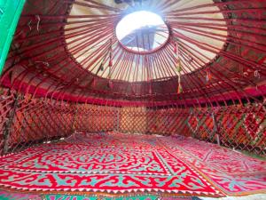 a room with a round window and a red and white rug at Azamat Yurt Camp in Song-Kul