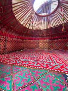 a room with a colorful floor with a round window at Azamat Yurt Camp in Song-Kul +2 photos