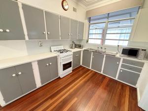 a kitchen with white cabinets and a stove top oven at Conns Cottage - Bring your own linen in South West Rocks