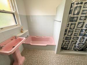 a bathroom with a pink tub and a sink at Conns Cottage - Bring your own linen in South West Rocks +8 photos