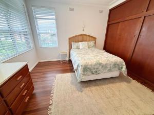 a bedroom with a bed and a large wooden cabinet at Conns Cottage - Bring your own linen in South West Rocks