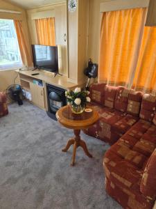 a living room with a couch and a table at Cabin Sleeps 6 with access outdoor Pool in Sandown