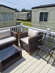 a deck with wicker chairs and a table and a chair at Cabin Sleeps 6 with access outdoor Pool in Sandown