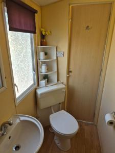 a bathroom with a toilet and a sink and a window at Cabin Sleeps 6 with access outdoor Pool in Sandown +7 photos