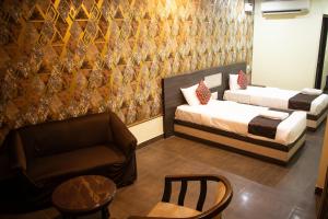 two beds in a room with a couch and a chair at Aira Suites in Bangalore
