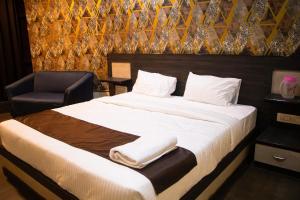 a bedroom with a large bed and a chair at Aira Suites in Bangalore