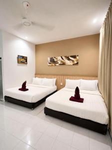 two beds in a hotel room with hats on them at The Dhania Cenang Beach Langkawi in Pantai Cenang