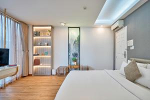 a bedroom with a white bed and a tv at Cactusland Boutique Hotel in Ho Chi Minh City
