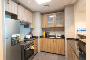 a kitchen with wooden cabinets and a stove top oven at Saadiyat Serenity 1BR apartment with Beach access in Abu Dhabi