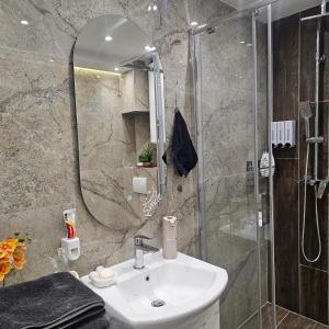 a bathroom with a sink and a shower with a mirror at Stan na dan Bijeljina centar 2 in Bijeljina +16 photos
