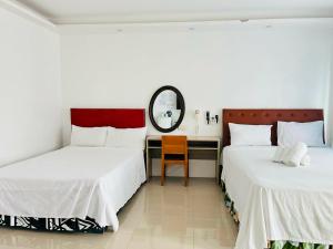 two beds in a room with a desk and a mirror at Shiri Hotel in Silang