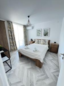 a white bedroom with a bed and a large window at Вила TIMeS in Kiten