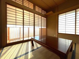 a large room with a wooden table and two windows at 蒼のSkyviewBase in Hiroshima