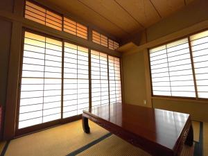 a room with a wooden table and two large windows at 蒼のSkyviewBase in Hiroshima