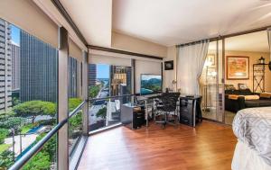 a bedroom with a balcony with a bed and a desk at Executive Center Hotel Honolulu in Honolulu