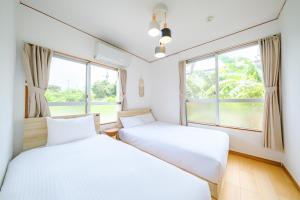 two beds in a room with two windows at ふんわり in Miyakojima