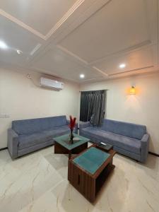 a living room with two blue couches and a table at hotel royal highness in Ahmedabad +1 photo