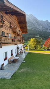 a building with a green lawn next to a house at Der Pfindlhof in Leogang