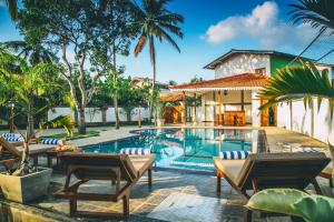 a swimming pool with chairs and a house at Sisikirana Villa (Luxury Villa in Galle) in Unawatuna