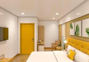 a bedroom with a bed and a yellow door at Bloom Hotel CMH Road Indiranagar in Bangalore
