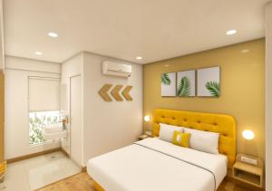 a bedroom with a white bed and a yellow headboard at Bloom Hotel CMH Road Indiranagar in Bangalore