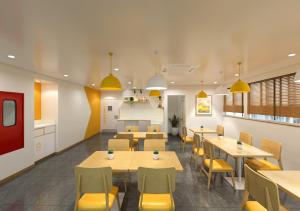 a restaurant with tables and chairs and yellow chairs at Bloom Hotel CMH Road Indiranagar in Bangalore