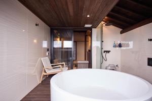 a bathroom with a white tub and a chair at いっぺ The Sake Ryokan in Kyonan +86 photos