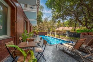 an outdoor patio with a swimming pool and chairs at De Amour - A Dreamy Getaway in Anjuna in Anjuna
