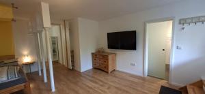 ein Wohnzimmer mit Fernseher und einer Kommode aus Holz in der Unterkunft Downstairs6b WIEDERERÖFFNUNG IM JULI ! in Dipperz